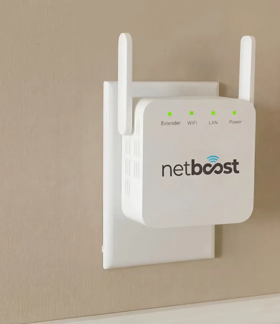 NetBoost Pro WiFi Extender plugged into a wall outlet, white with two antennas and four status lights